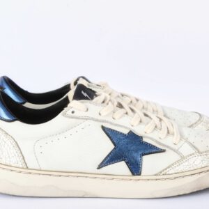 Witte sneakers met blauwe ster en beschadigde zool.