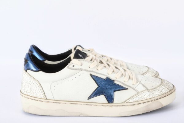 Witte sneakers met blauwe ster en beschadigde zool.