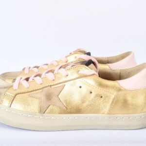 Gouden sneakers met roze veters en sterren.
