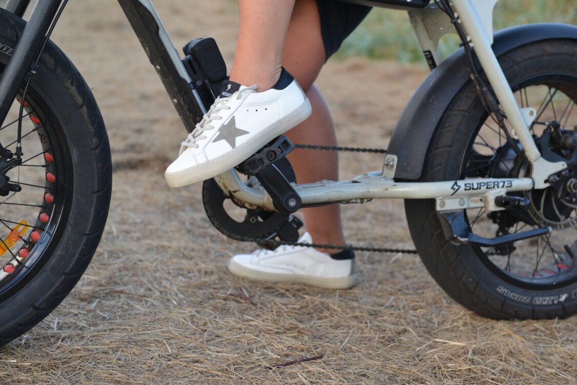 Persoon op fiets met witte sneakers